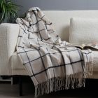 Plain Check Woven Throw, Natural & Blue draped over sofa against grey wall with plant